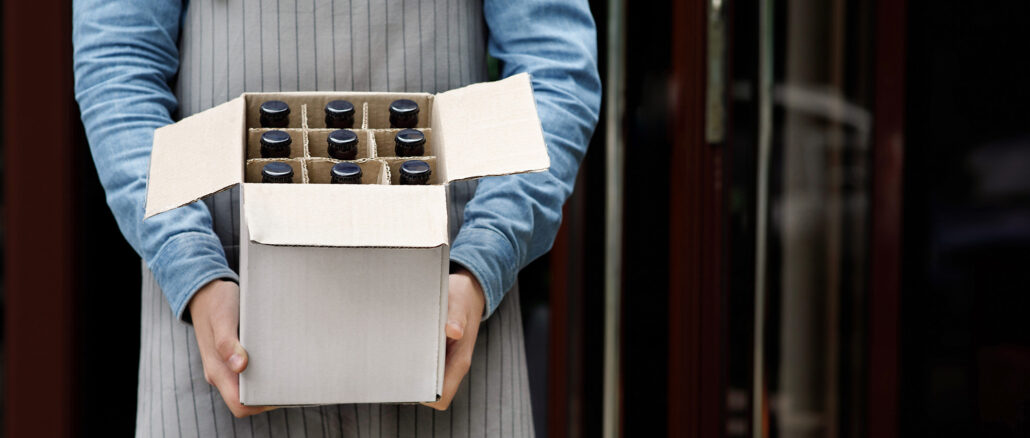 Beer for party at weekend. Bartender holds open cardboard box with bottles